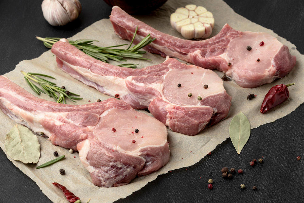 Три куска сырой баранины, рядом лавровые листья, горошины перца, чеснок, зелень и сушеный красный перец