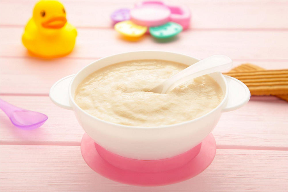 На столе тарелка с детским пюре из индейки, рядом находятся игрушки