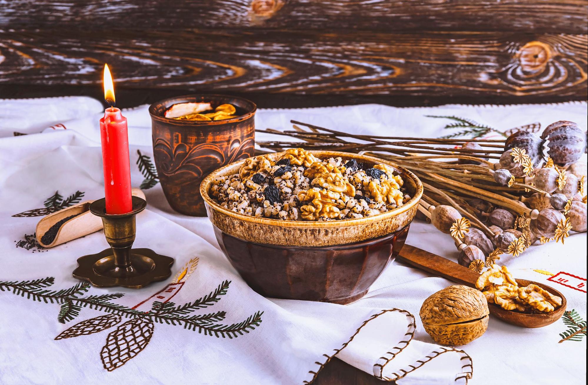 Праздничный стол со скатертью, каша в глиняной тарелке с орехами и маком, свеча и сухие маки