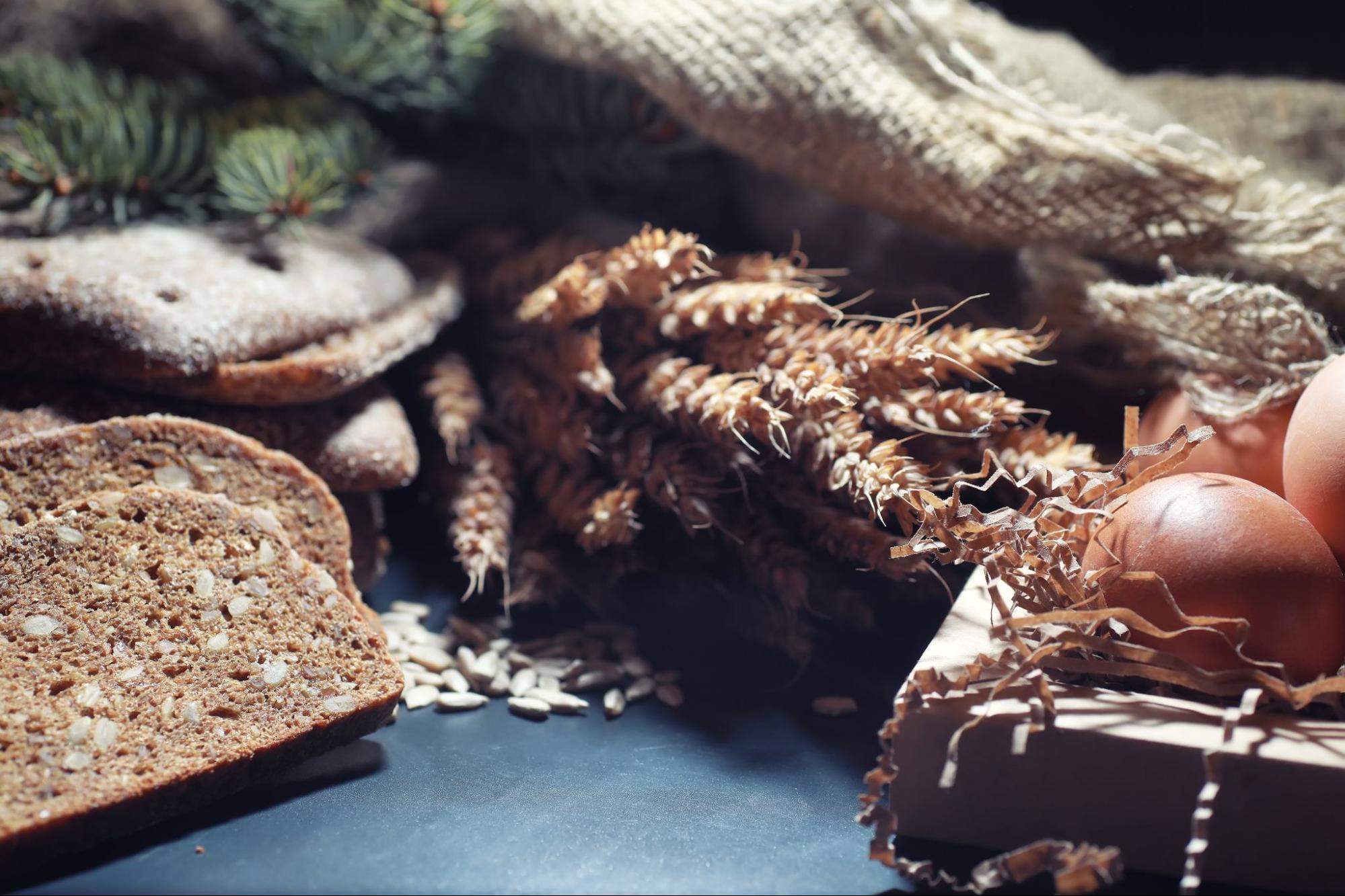 Хлеб с семечками, нарезанный ломтиками, ржаной хлеб, вареные яйца на темном деревянном столе