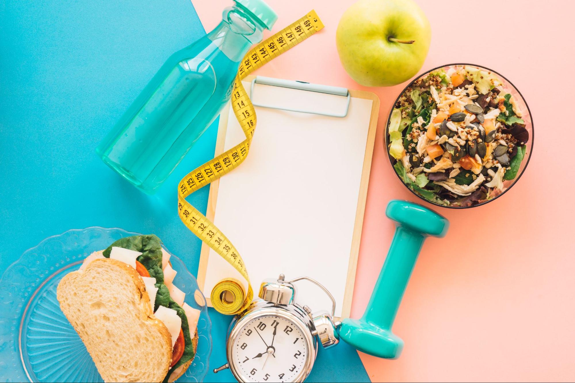 Будильник, салат, фитнес-бутылка, гантели, метрика, яблоко на цветном фоне