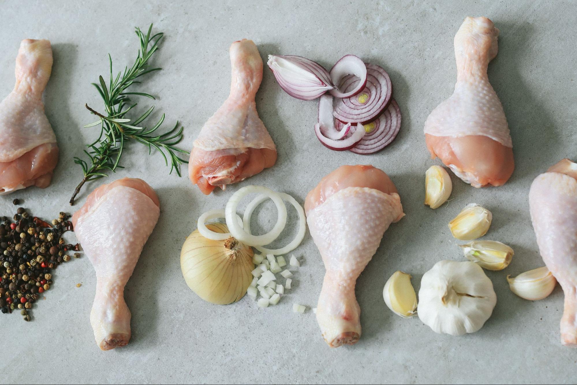Куриные ножки, специи, лук и чеснок на столе