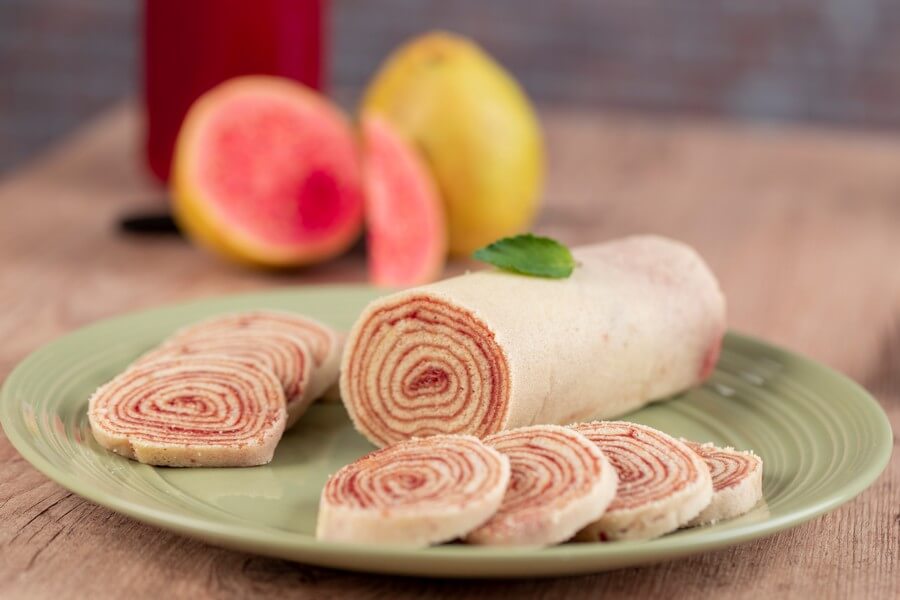 Аппетитный сладкий рулет пастилы, украшенные листьями мяты и дольками фруктов, поданные на зеленой тарелке