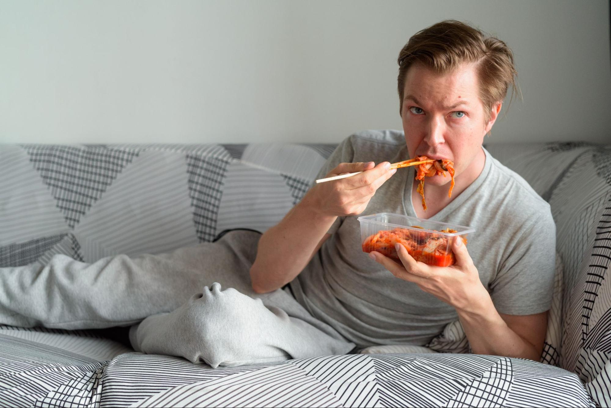 Мужчина ест на диване